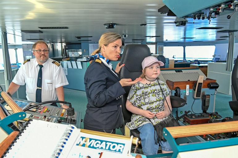 Silja Serenaden intendentti Taru Backmann kertoo Iirikselle laivasta komentosillalla. Kapteeni Juha Rantavirta seuraa taustalla, kun jännittynyt pikku-Iiris pääsee istumaan oikein kapteenin tuolille.