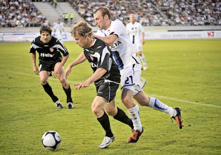 Vuonna 2009 Konsta (musta paita) pelasi jalkapallon Eurooppa-liigan karsintaottelussa belgialaista Bruggea vastaan. Taustalla tilannetta tarkkailee Jari Litmanen.