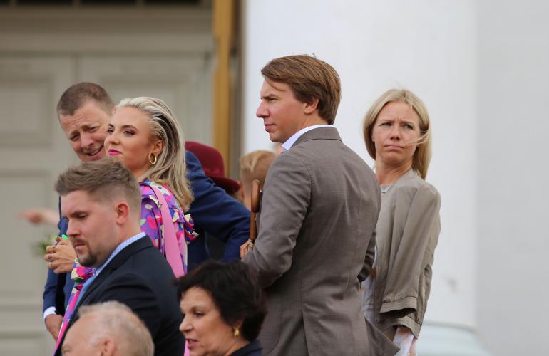 Toimittaja Sonja Kailassaari kurkki puolisonsa Aku Hirviniemen takaa tuiman oloisena.
