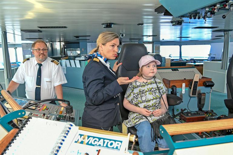 Silja Serenaden intendentti Taru Backmann kertoo Iirikselle laivasta komentosillalla. Kapteeni Juha Rantavirta seuraa taustalla, kun jännittynyt pikku-Iiris pääsee istumaan oikein kapteenin tuolille.