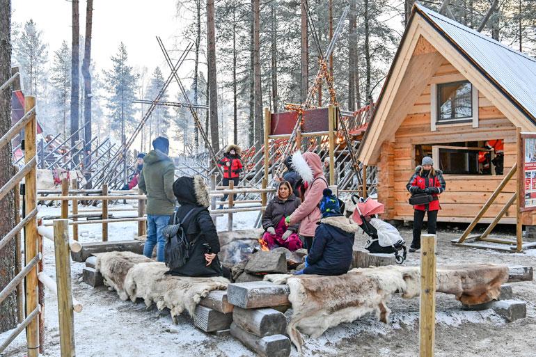 Intialaisturistit lämmittelevät nuotion ääressä odotellessaan pääsyä poroajelulle.
